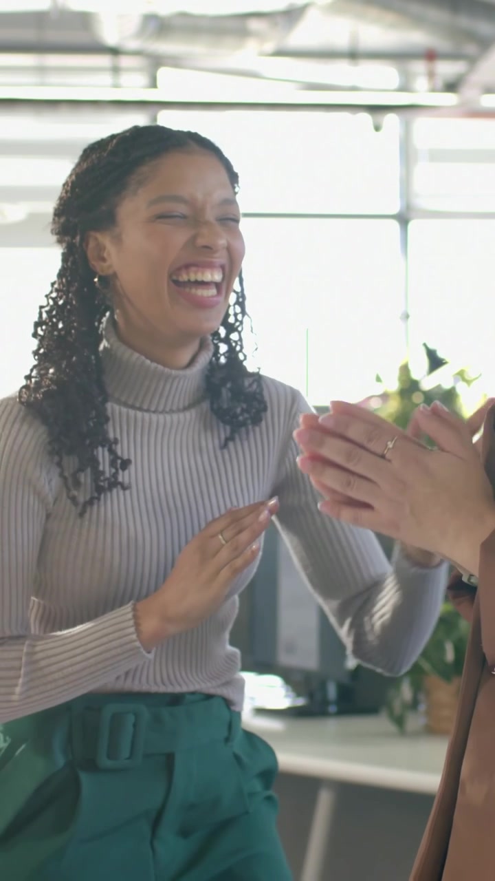 Video verticale: Donna in top grigio a una riunione, si batte il cinque, applaude e ride, festeggiando in ufficio.