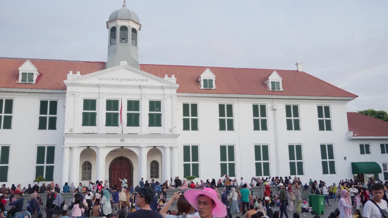 Crowd of people gathers at Taman Fatahillah in front of the historic colonial building in Jakarta