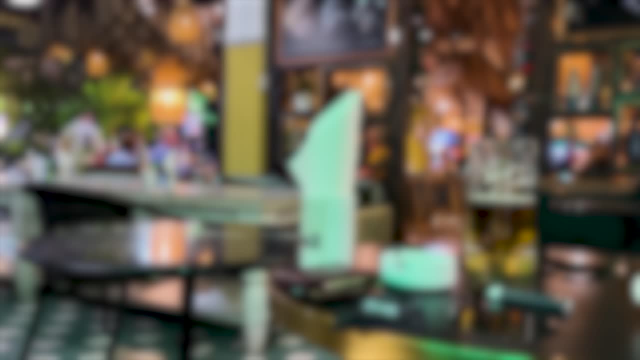 A blurred view of an outdoor restaurant setting, featuring ambient evening lighting and a relaxed atmosphere