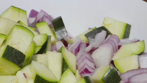 freshly cut courgette zucchini and red onions in bowl ready to cook - 4k high quality clip