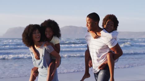 Madre-Y-Padre-Afroamericanos-Dando-Un-Paseo-A-Cuestas-A-Su-Hija-Y-Su-Hijo-En-La-Playa