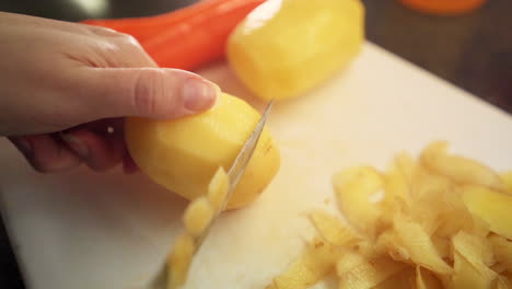 cerrar manos femeninas pelando patatas en la cocina en cámara lenta