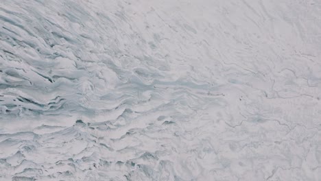 Aerial-landscape-view-over-ice-textures-and-formations-in-Virkisjokull-glacier-covered-in-snow,-Iceland