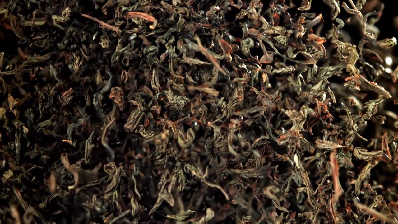 Dried Tea Leaves Falling in Slow Motion on Black Background