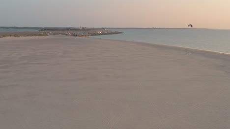 drone cinemático - toma aérea de la playa natural verde y arenosa al atardecer con buggykiting en zelanda en el mar del norte, países bajos, 30p
