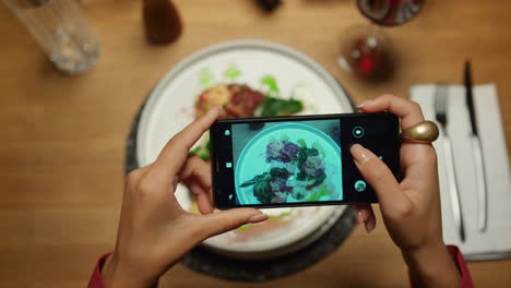 mujer tomando fotos de la cena usando el teléfono móvil en el restaurante. dama disfrutando de la comida.