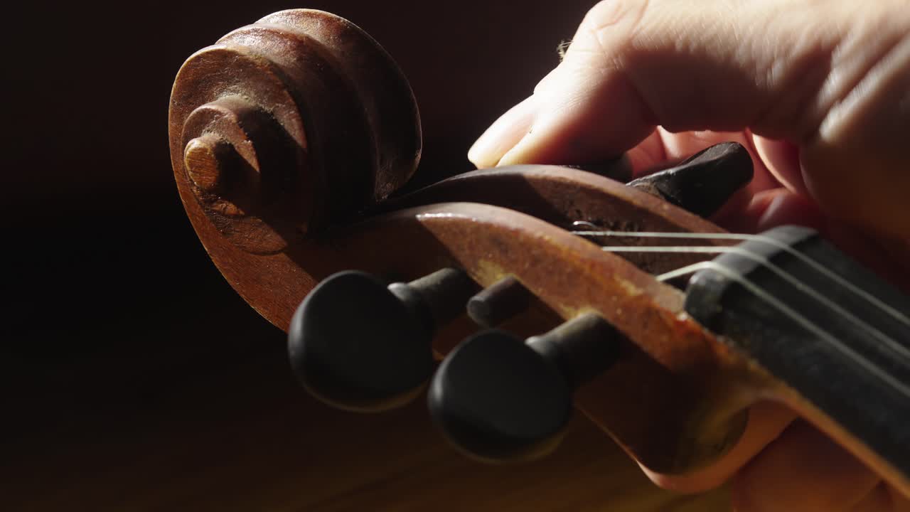 Musician adjusting and tuning nylon strings on violin Close-Up