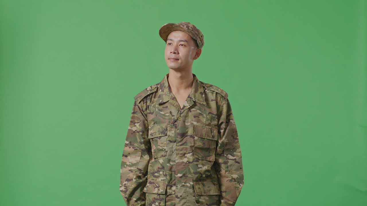 Asian Man Soldier Looking Around While Standing In The Green Screen Background Studio