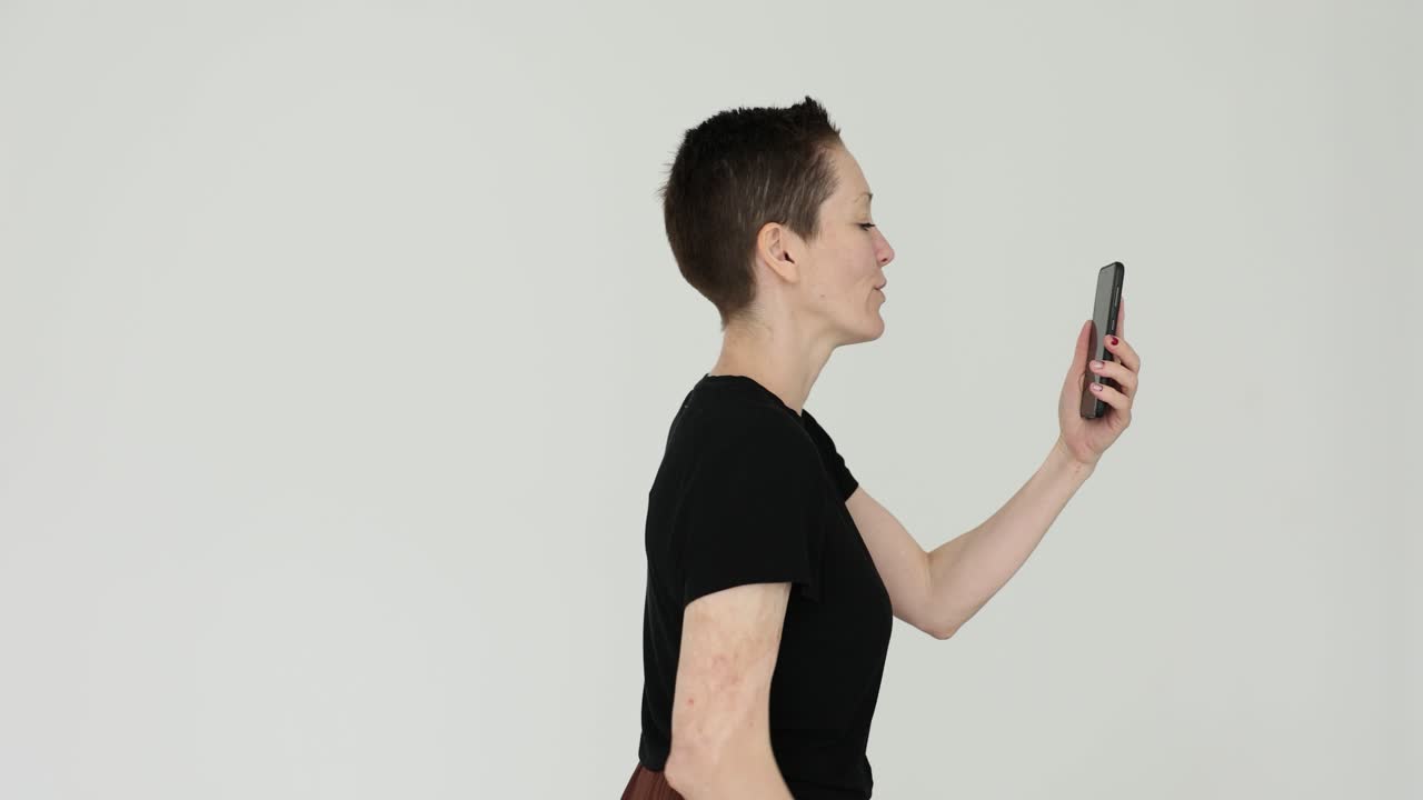 Woman making a video call on her smartphone, waving and talking