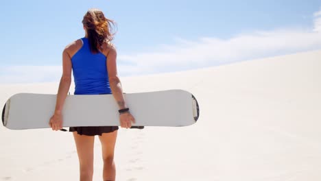 woman walking with sand board in the desert 4k