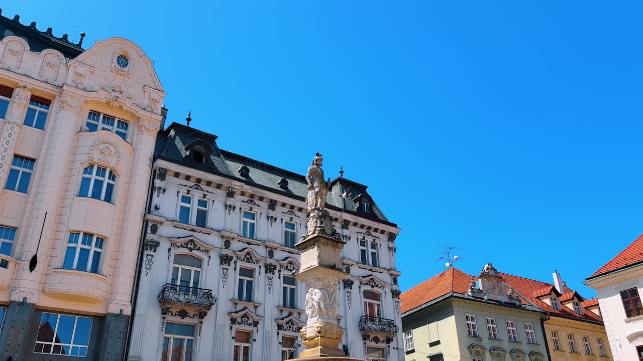 A monument on the fountain at the backdrop of beautiful buildings. Old town architecture in Bratislava, Slovakia