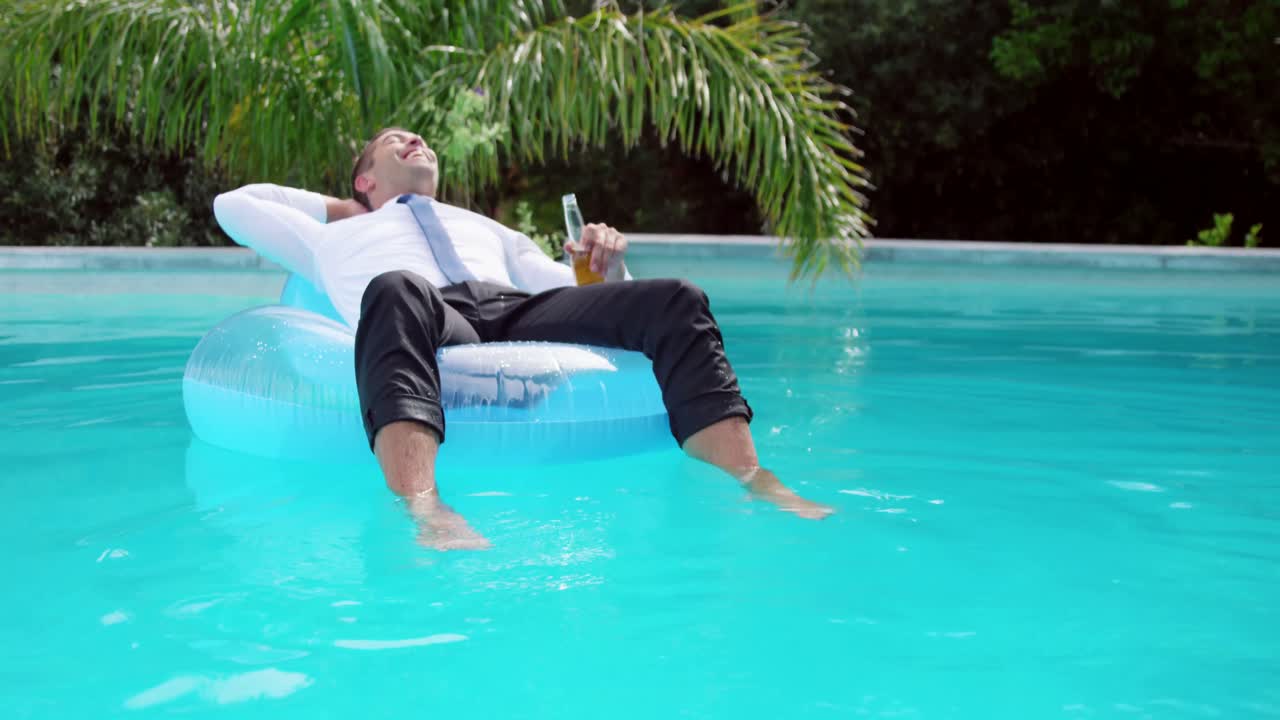 Businessman lying on lilo in swimming pool