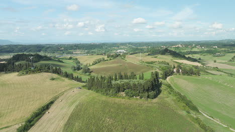 hilly landscape with green meadows and fields near rural town in italy