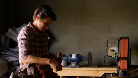 female metalsmith using mobile phone in factory 4k