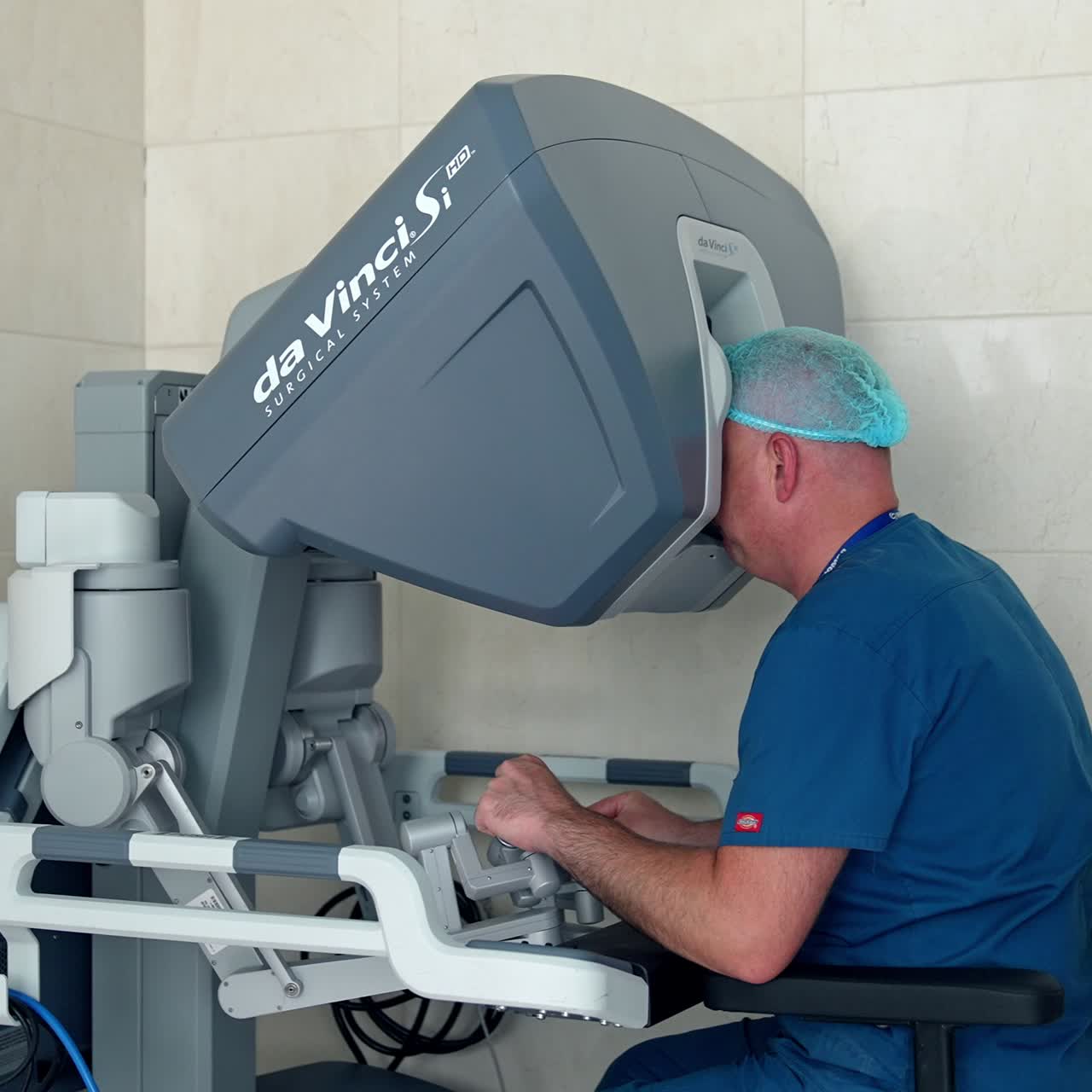 Approaching the medical specialist sitting at modern apparatus. Doctor moves little handles to operate Da Vinci robot