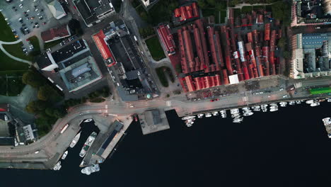 top down tracking shot of a small port with boats, houses and some factory buildings can be seen from above, daytime, no people