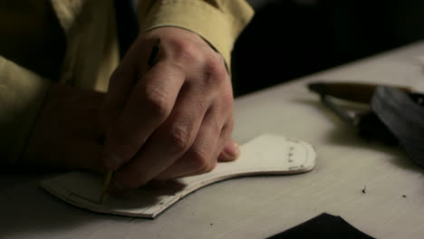 Leatherworker-making-slots-in-leather-blank.-Close-up-shoemaker-hands-at-work