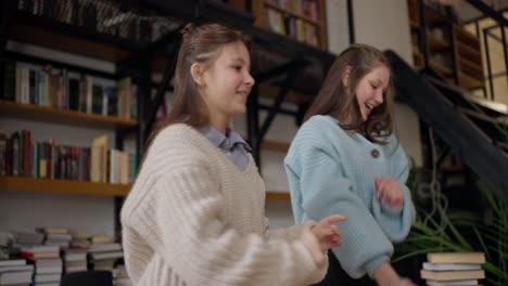 two teen girls dancing in a library