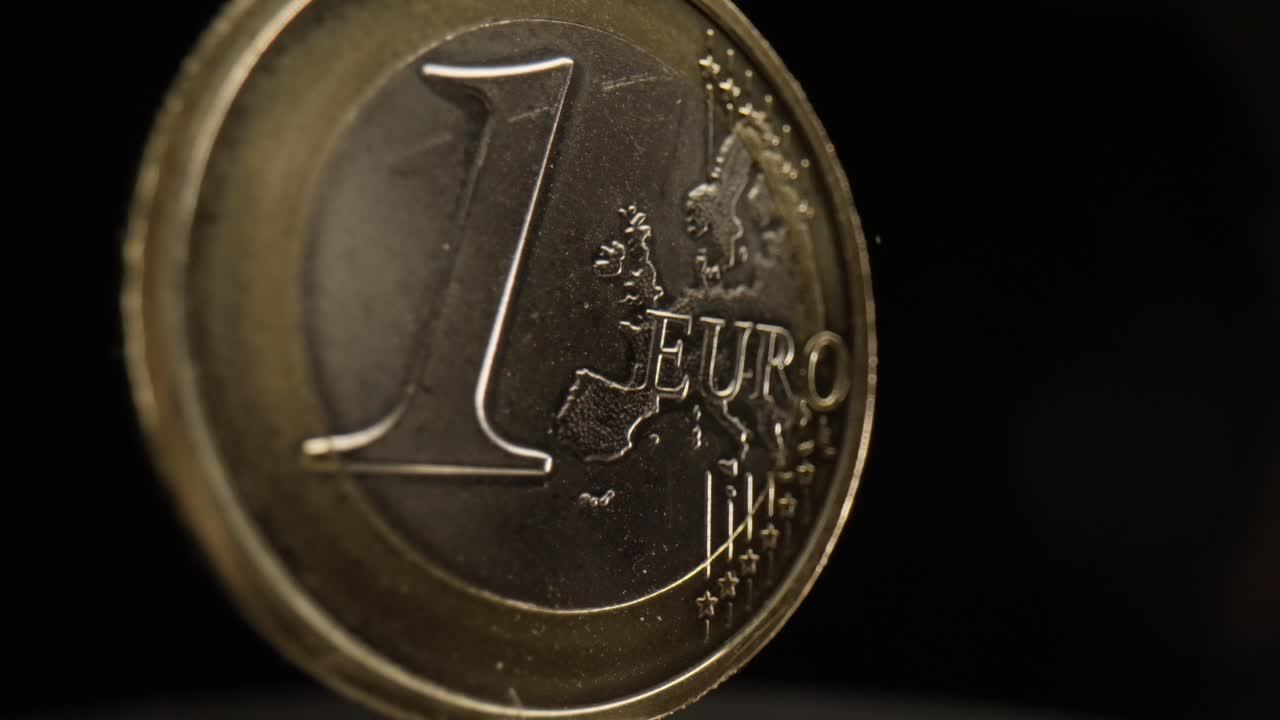 primer plano de una moneda de 1 euro con un fondo negro que está girando