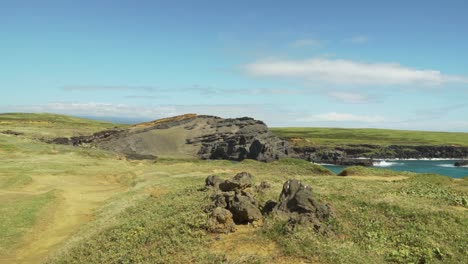 The-remains-of-a-very-old-volcano-that-has-now-turned-into-a-green-sand-beach-with-clear-blue-water-and-surrounded-by-grasslands