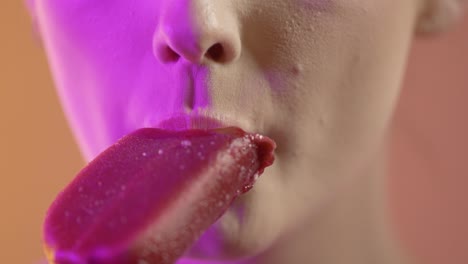 woman's mouth eating flavored popsicle ice cream, close up colorful studio shot