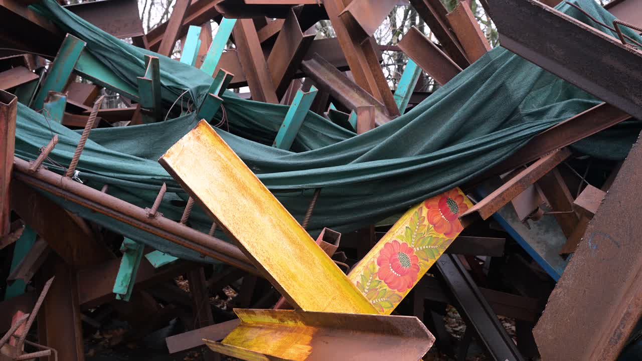 A yellow-painted anti-tank barricade with flower drawings stands among stacked barricades on a Kyiv street amid the Ukraine-Russia war.