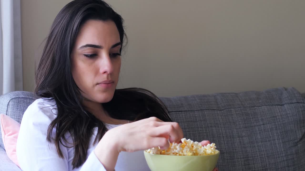 Donna che mangia popcorn mentre guarda la TV 4k