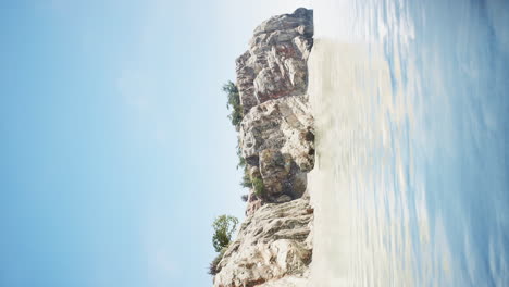 Vista-Vertical-Del-Paisaje-Marino-Con-Agua-Turquesa-Y-Isla-De-Roca-Tropical