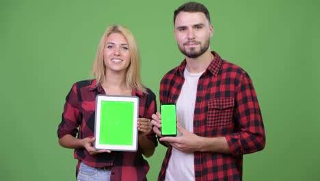 young couple showing digital tablet and smart phone together
