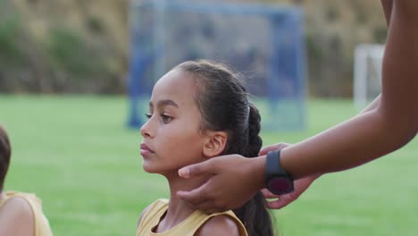 Mixed-race-female-teacher-correcting-diverse-group-of-schoolchildren-while-yoga-stretching-outdoors