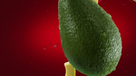 aguacate con rebanadas y salpicaduras cayendo sobre un fondo rojo profundo
