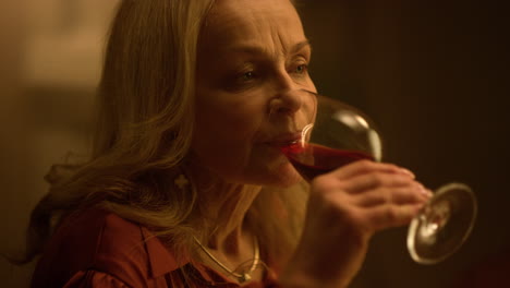 mujer vieja bebiendo una copa de vino tinto en una cita en un restaurante.