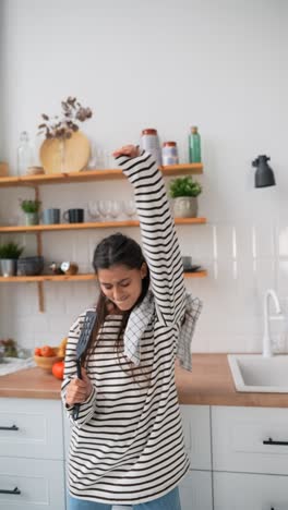 mujer feliz cantando y bailando en la cocina
