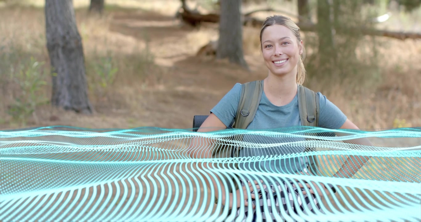 Hiker wearing backpack in forest clearing seeing tech mesh overlay appearing and inspiring smile
