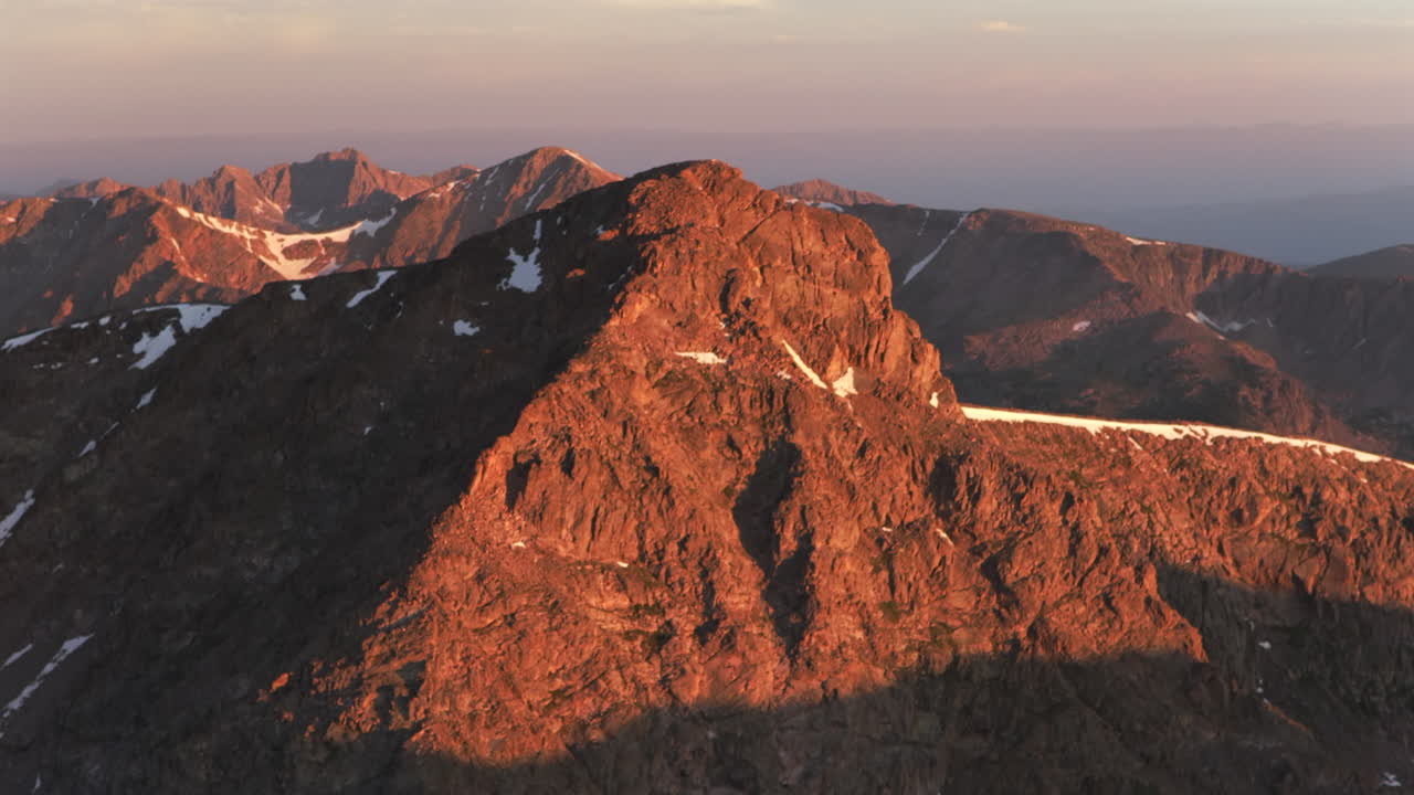 Sunrise summertime Mount of the Holy Cross 14er peak aerial drone parallax jib up motion first light on Sawatch Range Rocky Mountain 14er peak summit North Ridge Trail early morning golden hour snow