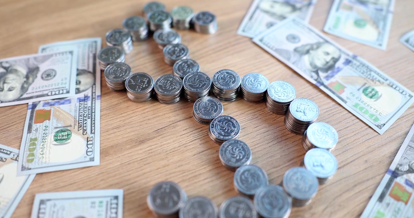 Arreglo creativo de monedas y billetes formando un símbolo de dólar sobre una superficie de madera.