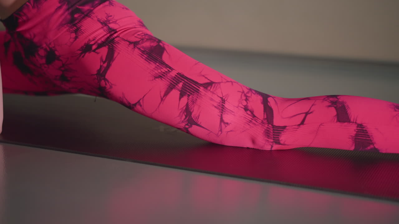 wanita kulit putih melakukan split kaki di matras di studio dengan legging dan kaus kaki berpola merah muda, jari kaki menunjuk, ketegangan hamstring, keselarasan presisi, suasana latihan yang terfokus dan praktik mobilitas yang disiplin