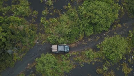 drone aerial bird's-eye view of a car driving off-road over volcanic sand in a forest during camping trip to pacaya volcano, guatemala