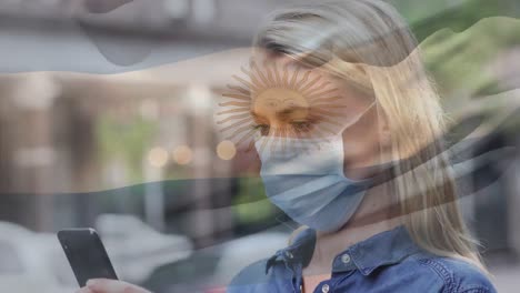 animation of flag of argentina waving over caucasian woman wearing face mask in city street