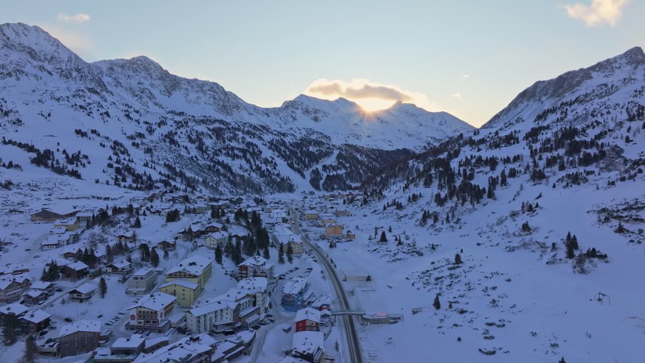 Pastellfärgad soluppgång över vinterbyn Obertauern och snöklädda toppar