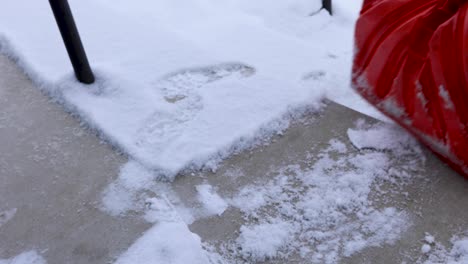 shoveling snow off of stairs in front of apartment