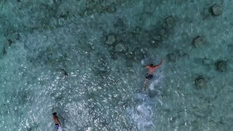 Two-young-male-swimmers-enjoy-crystal-clear-water-on-holiday,-Palms-island-beach