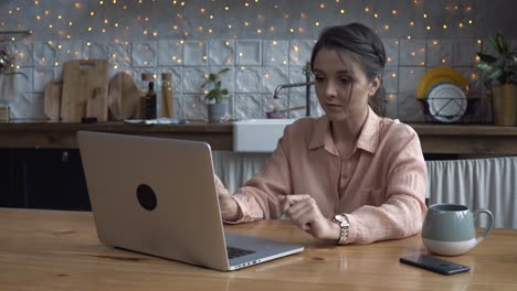 woman working on laptop in a cozy kitchen