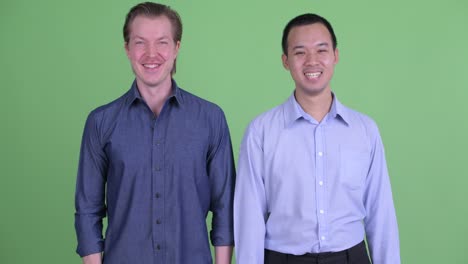 two businessman smiling against green studio background