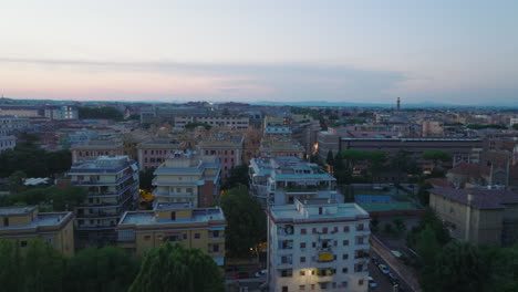 Control-Deslizante-De-Ciudad-Urbana-En-El-Crepúsculo.-Vista-Aérea-De-Edificios-De-Apartamentos-Y-árboles-Verdes-En-El-Parque.-Roma,-Italia