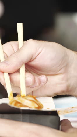 person eating takeout food with chopsticks