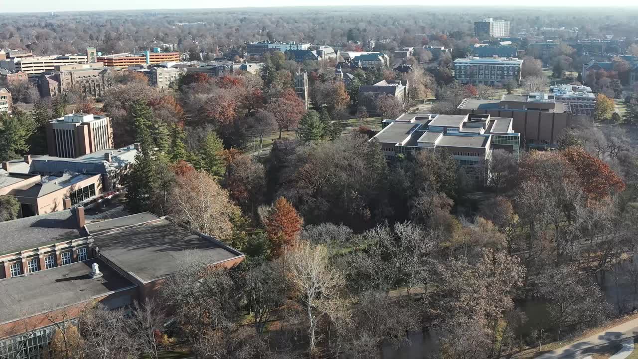 Wide aerial view showcasing Beaumont Tower and surrounding Michigan State University campus landscapes in smooth, cinematic motion
