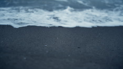 Weiße-Welle,-Die-Auf-Den-Strandsand-Trifft.-Blaue-Meerwasseroberfläche,-Die-An-Der-Küste-Plätschert.