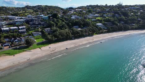 people and beachfront properties at big oneroa beach on oneroa bay in auckland, new zealand