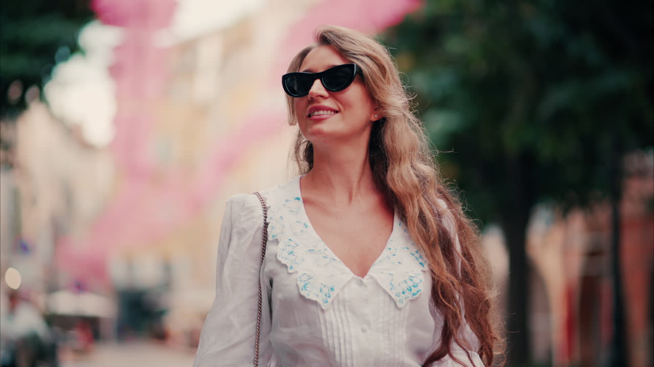 Woman walking under rows of pink umbrellas above the streets of the old town of Grasse, France